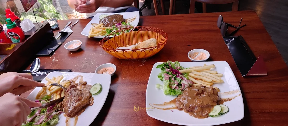 버섯 소스 스테이크 세 접시가 놓인 다낭 PapaSteak 테이블
